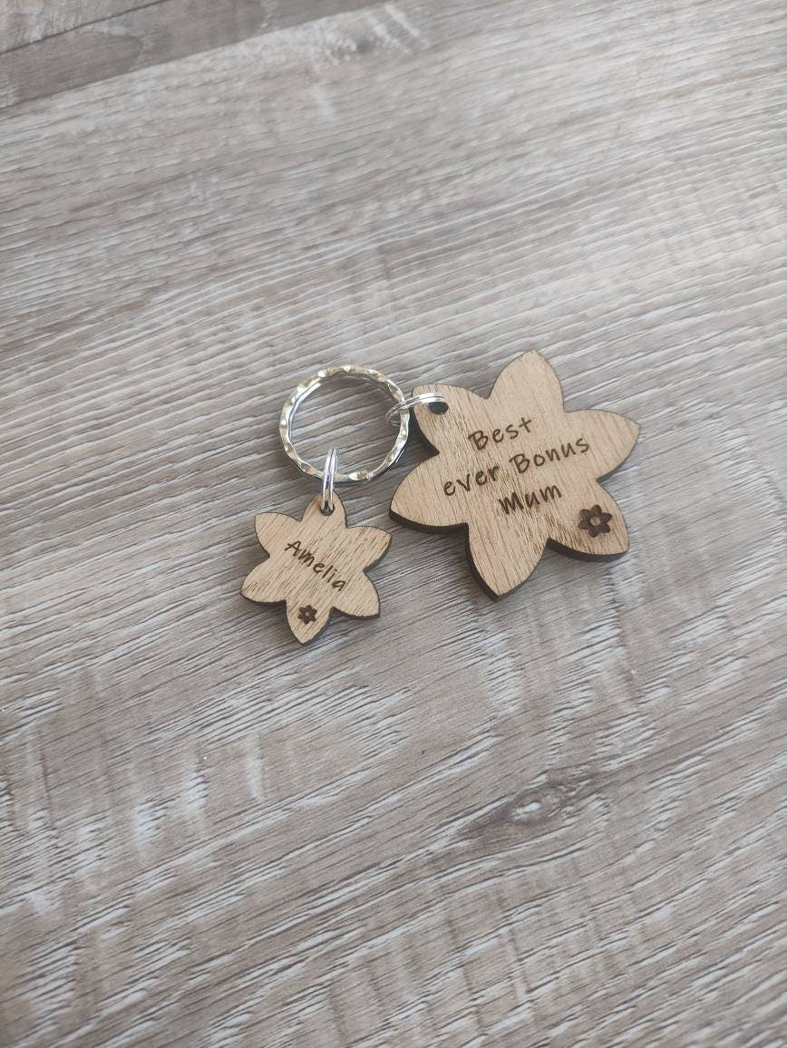 Flower-shaped keyring with "Best Ever Bonus Mum" engraved, featuring smaller charms with a child's name.