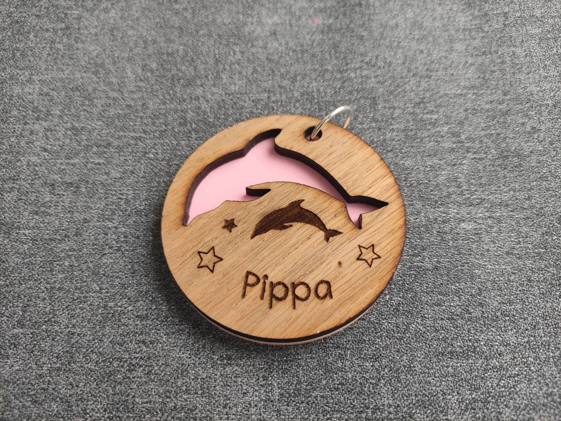 Circle keyring with a cut-out dolphin shape, backed with coloured acrylic, engraved with any name.