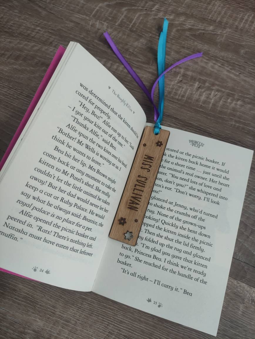 Personalised wooden bookmark engraved with flower designs, featuring two coloured ribbons tied at the top. A thoughtful and custom gift for book lovers, made from high-quality wood.