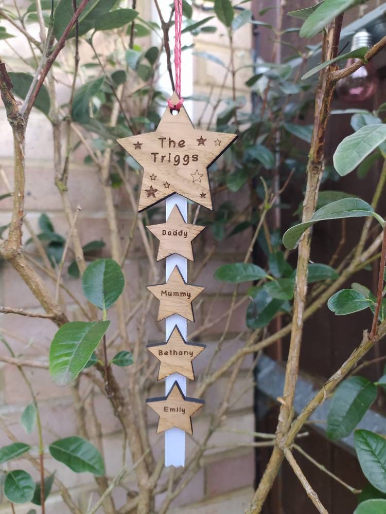 "Personalised Family Christmas Star Tree Hanger with laser-cut stars, custom engraved with family names, featuring red, white, or green hanging string."