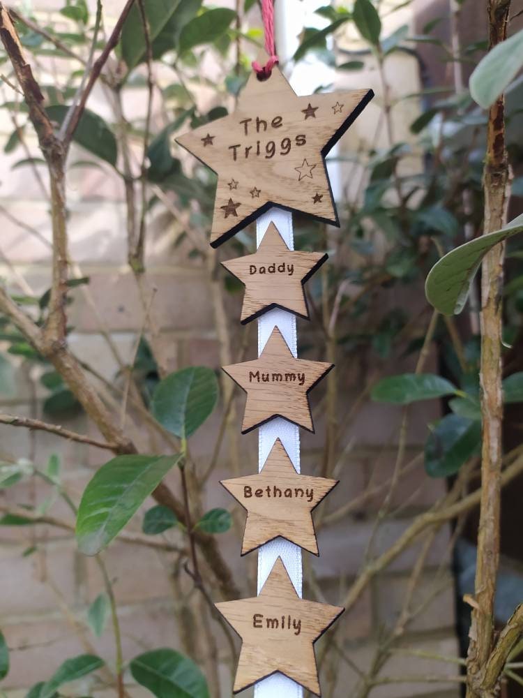 "Personalised Family Christmas Star Tree Hanger with laser-cut stars, custom engraved with family names, featuring red, white, or green hanging string."