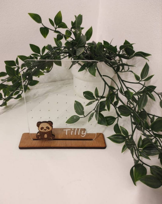 Clear acrylic earring holder with a custom engraved name across the bottom and a detailed panda design. Holds multiple pairs of earrings, combining functionality with a cute, stylish touch. Made from 100% recycled acrylic.