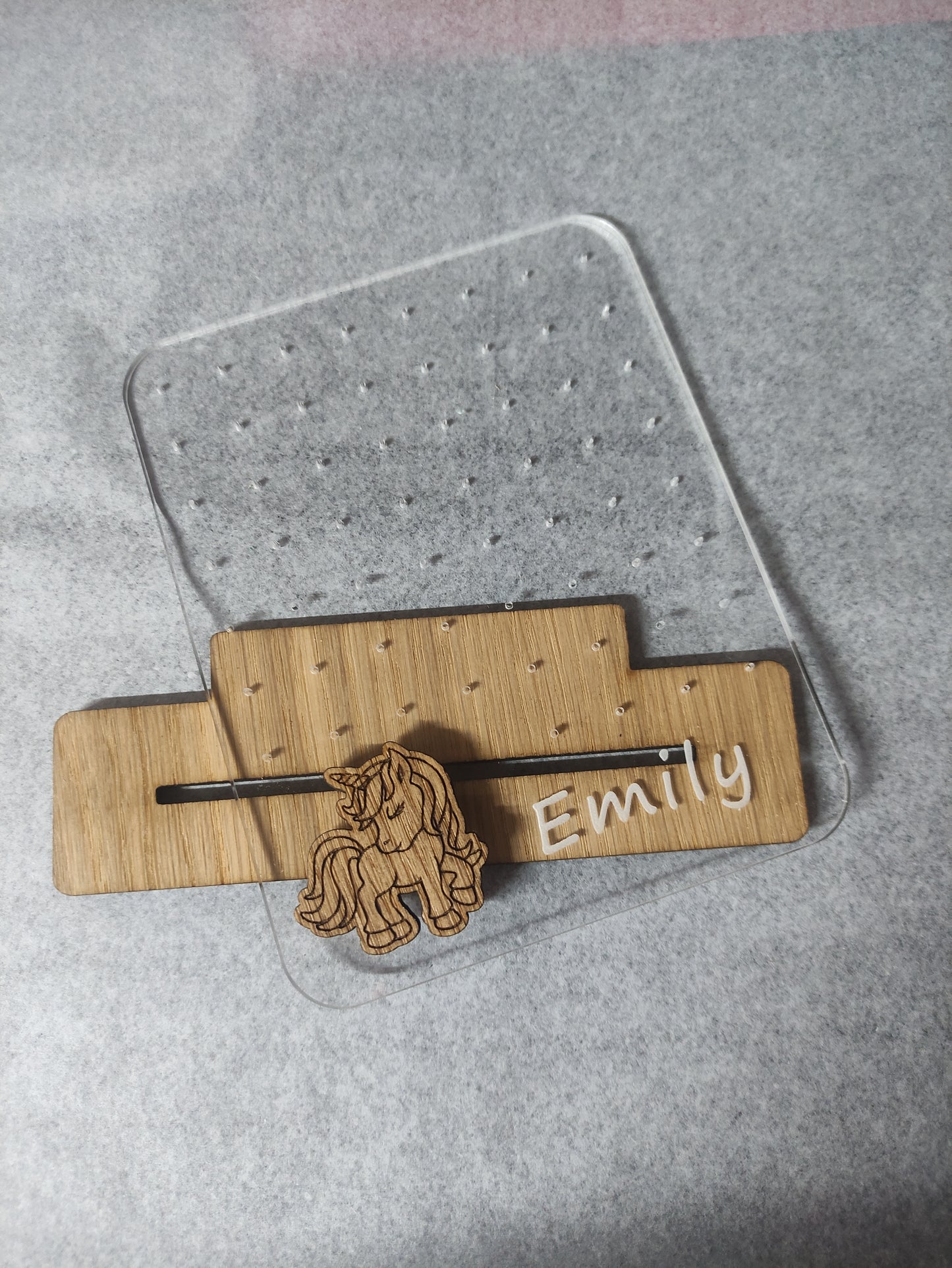 Clear acrylic earring holder with a custom engraved name across the bottom and a detailed unicorn design. Holds multiple pairs of earrings, combining functionality with a cute, stylish touch. Made from 100% recycled acrylic.