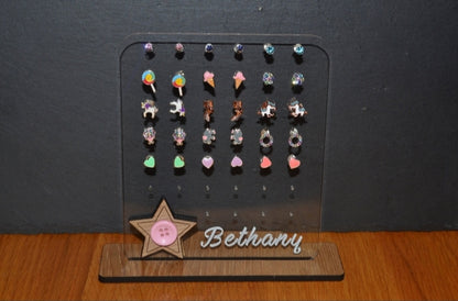 Clear acrylic earring holder with a custom engraved name across the bottom and a detailed star design. Holds multiple pairs of earrings, combining functionality with a cute, stylish touch. Made from 100% recycled acrylic.