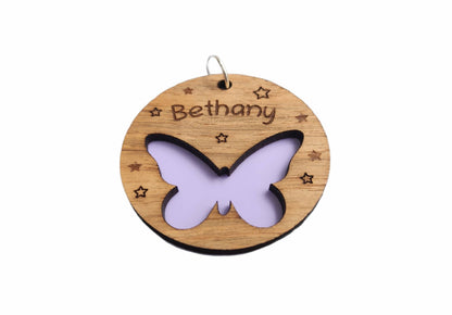 Circular keyring featuring a cut-out butterfly design backed with colourful acrylic, laser engraved with a personalised name on oak veneer.