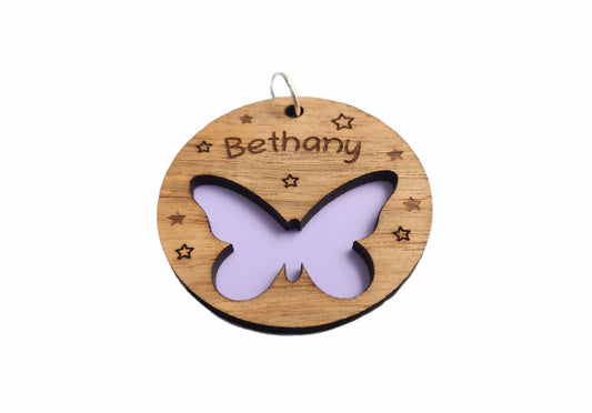 Circular keyring featuring a cut-out butterfly design backed with colourful acrylic, laser engraved with a personalised name on oak veneer.