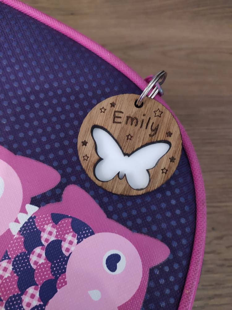 Circular keyring featuring a cut-out butterfly design backed with colourful acrylic, laser engraved with a personalised name on oak veneer.