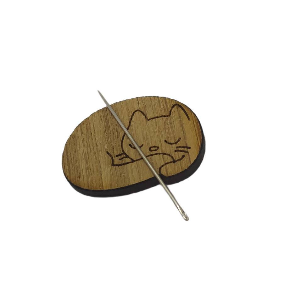 Cat-shaped needle minder with a strong magnet to hold needles, perfect for embroidery and cross-stitch projects.