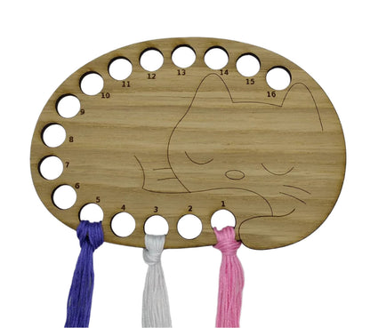 Cat thread holder in a sleeping cat design with 16 holes for thread.