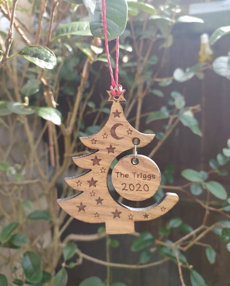 "Personalised Christmas tree bauble with custom name engraved, made from natural wood or clear acrylic."