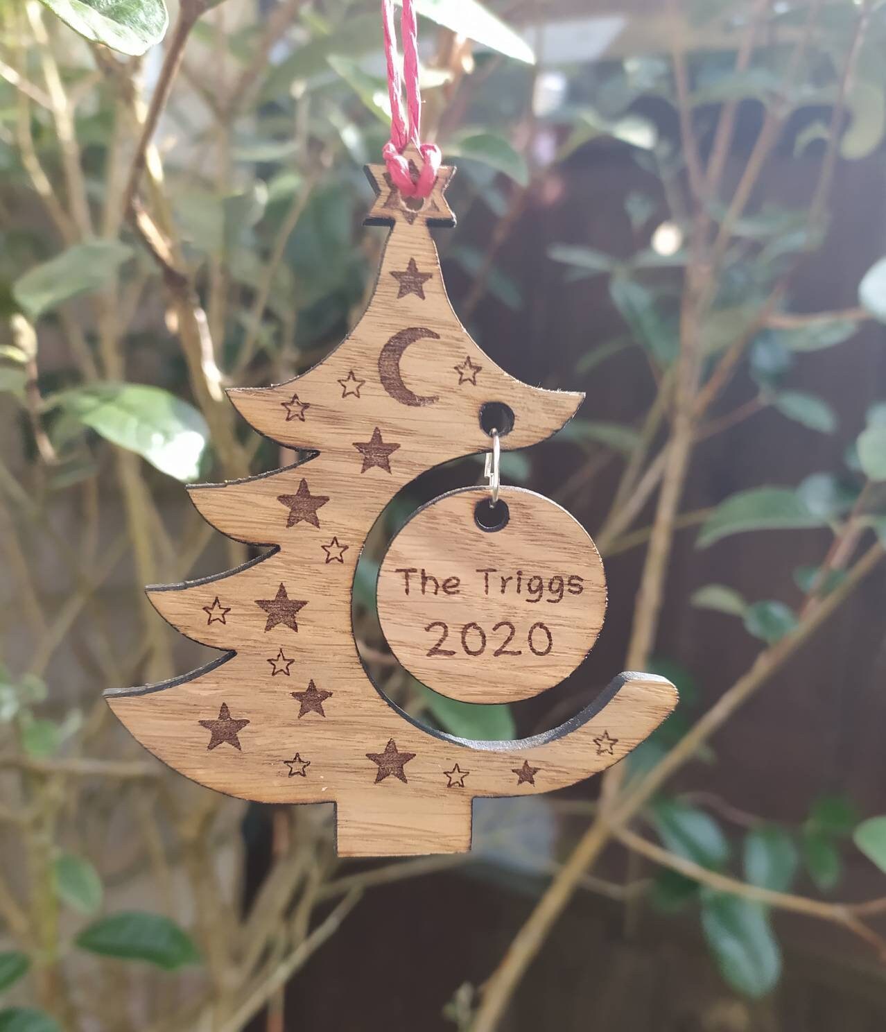 "Personalised Christmas tree bauble with custom name engraved, made from natural wood or clear acrylic."