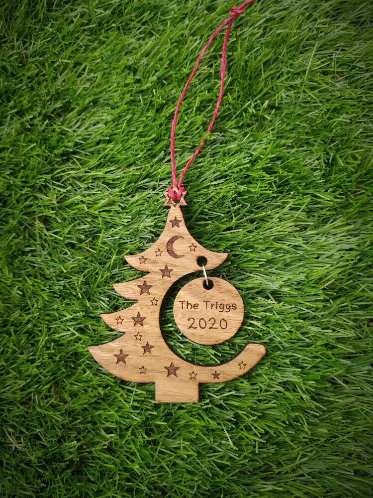 "Personalised Christmas tree bauble with custom name engraved, made from natural wood or clear acrylic."