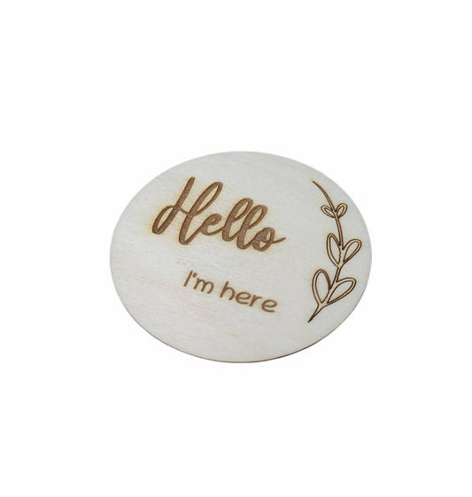 Personalised wooden milestone markers, engraved on 3mm plywood with a natural wood finish. Sized at 70mm x 70mm, they feature designs like 'Hello, I'm here' and other customisable options.