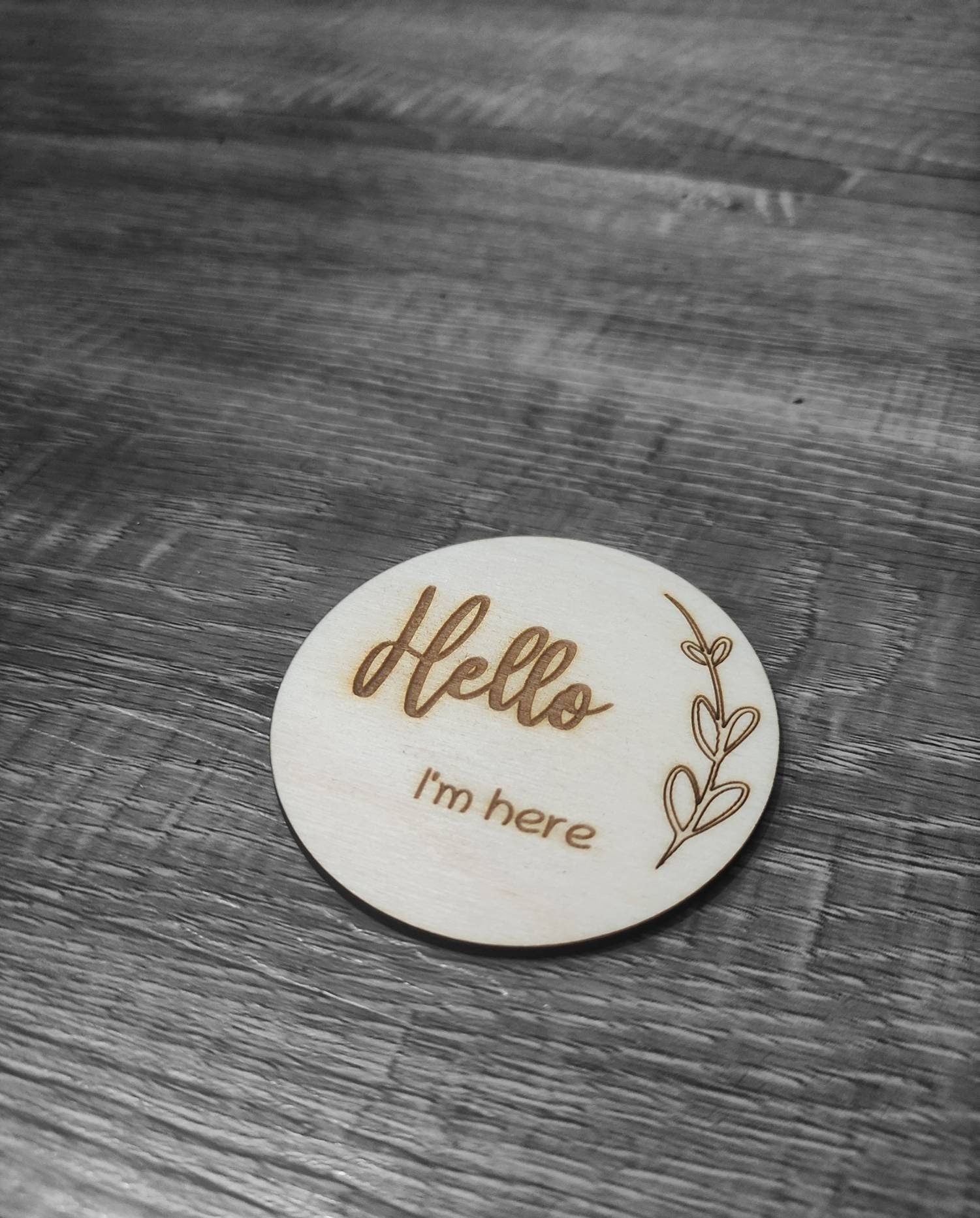 Personalised wooden milestone markers, engraved on 3mm plywood with a natural wood finish. Sized at 70mm x 70mm, they feature designs like 'Hello, I'm here' and other customisable options.