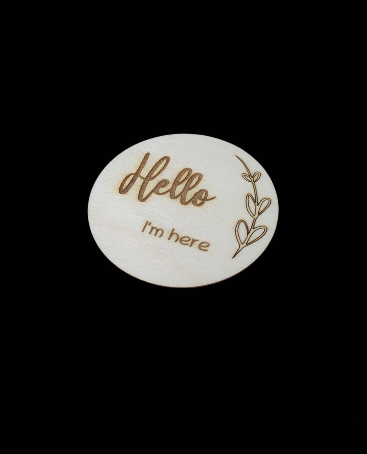 Personalised wooden milestone markers, engraved on 3mm plywood with a natural wood finish. Sized at 70mm x 70mm, they feature designs like 'Hello, I'm here' and other customisable options.