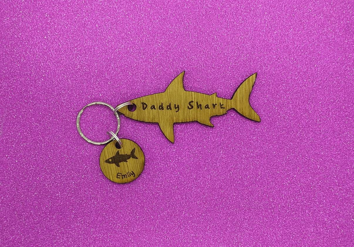 Shark-shaped keyring with "Daddy Shark" engraved in the middle, featuring added circle charms with a name and shark design engraved.