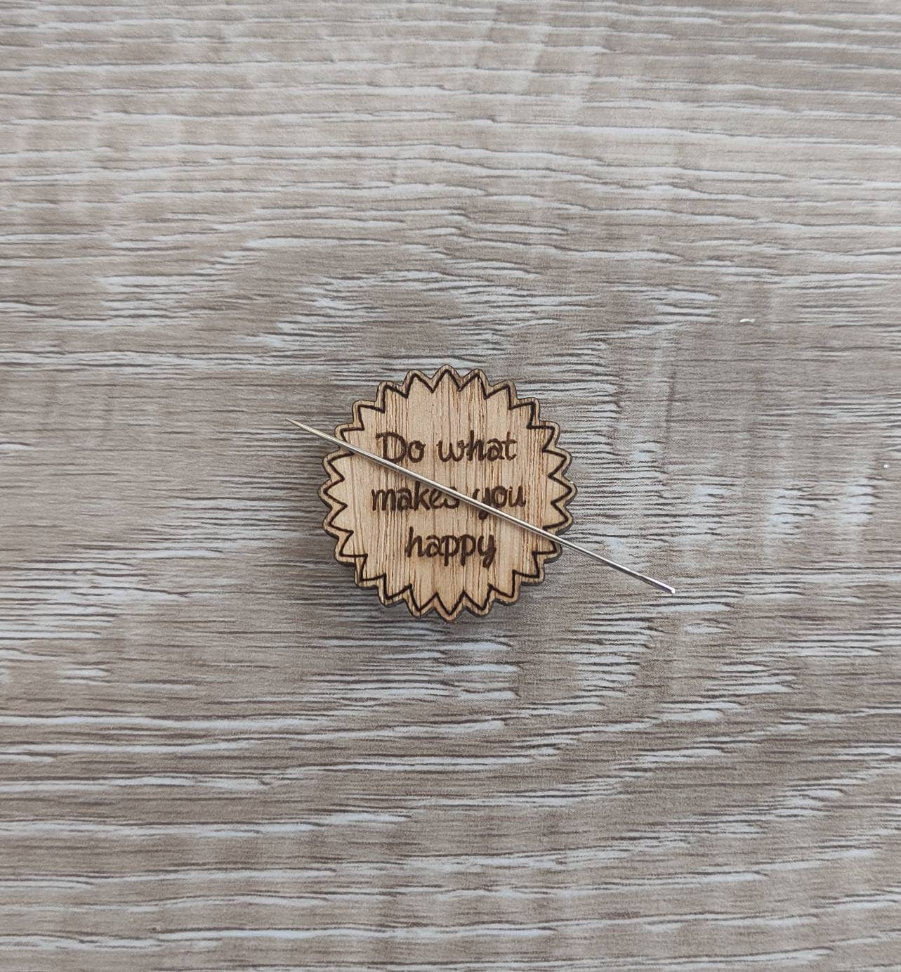 Round soft jagged edges needle minder with "Do What Makes You Happy" engraved: