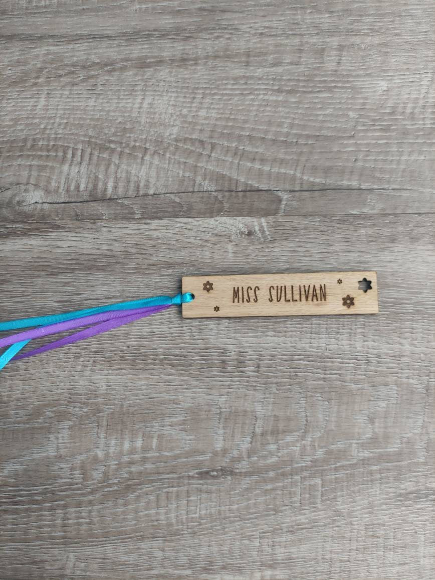 Personalised wooden bookmark engraved with flower designs, featuring two coloured ribbons tied at the top. A thoughtful and custom gift for book lovers, made from high-quality wood.
