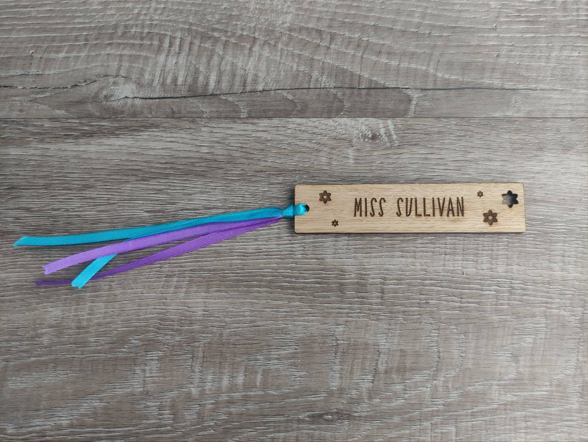 Personalised wooden bookmark engraved with flower designs, featuring two coloured ribbons tied at the top. A thoughtful and custom gift for book lovers, made from high-quality wood.