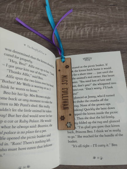Personalised wooden bookmark engraved with flower designs, featuring two coloured ribbons tied at the top. A thoughtful and custom gift for book lovers, made from high-quality wood.