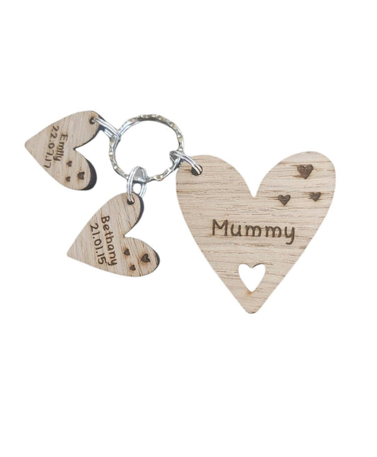 Personalised heart-shaped wooden keyring engraved with "Mummy" and customisable with charms featuring a child’s name and date of birth.