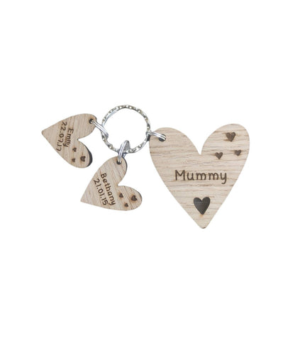 Personalised heart-shaped wooden keyring engraved with "Mummy" and customisable with charms featuring a child’s name and date of birth.