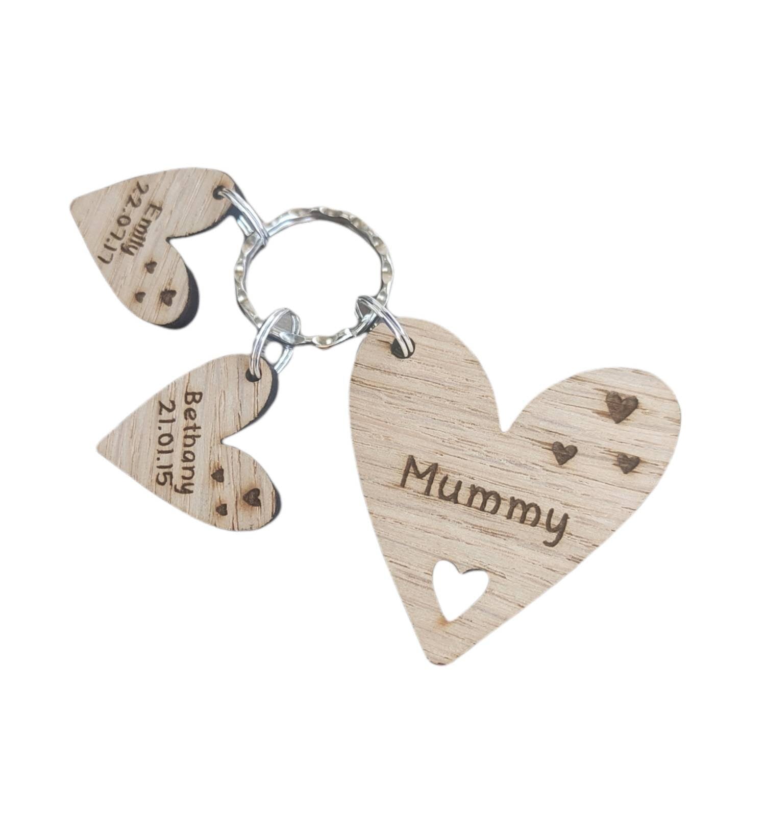 Personalised heart-shaped wooden keyring engraved with "Mummy" and customisable with charms featuring a child’s name and date of birth.