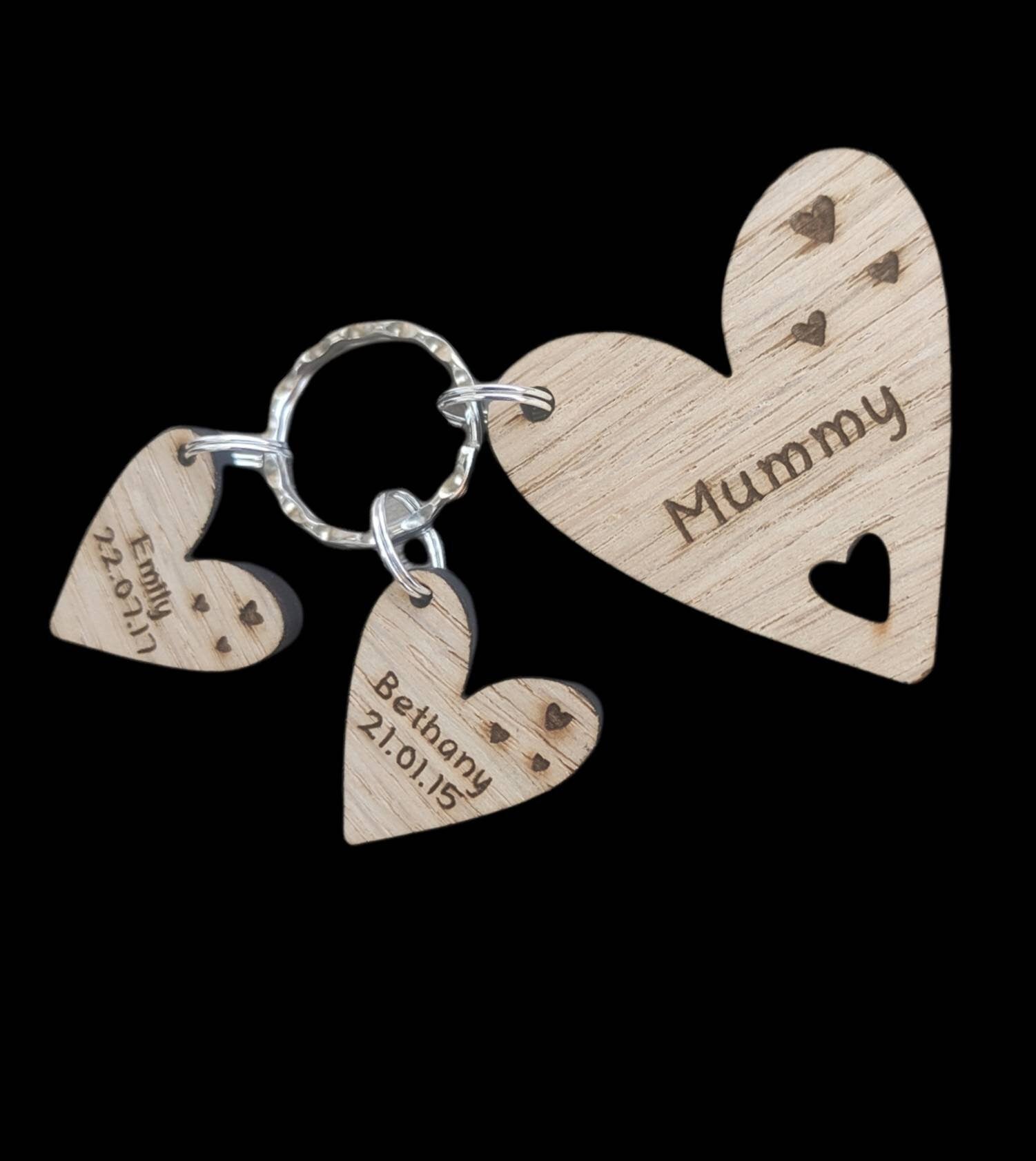 Personalised heart-shaped wooden keyring engraved with "Mummy" and customisable with charms featuring a child’s name and date of birth.