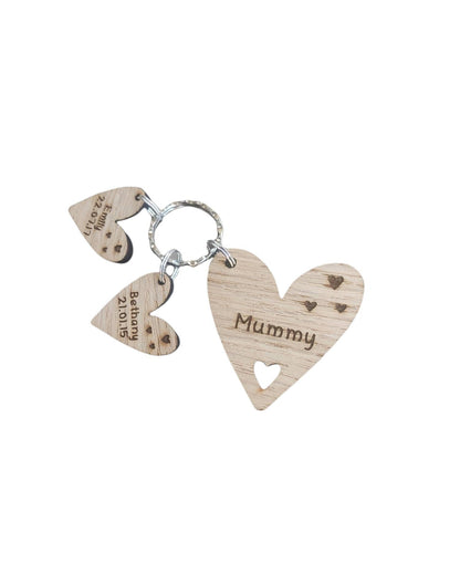  Personalised heart-shaped wooden keyring engraved with "Mummy" and customisable with charms featuring a child’s name and date of birth.