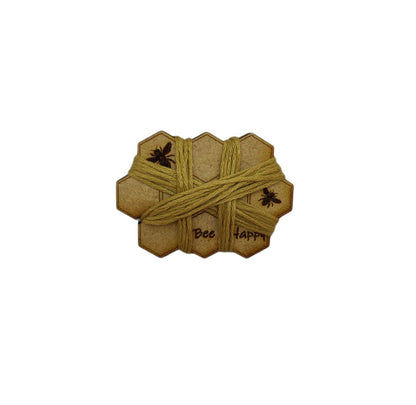 Honeycomb-shaped bobbin for keeping your thread tidy, engraved with bees and 'Bee Happy' design.