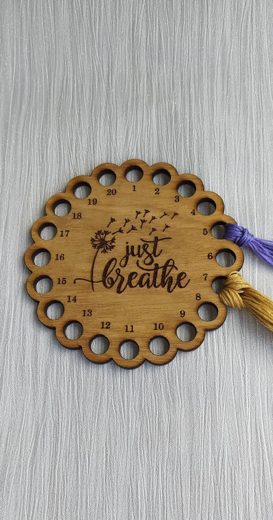 Thread holder in a flower shape with "Just Breathe" engraved, featuring 20 holes for thread.