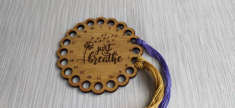 Thread holder in a flower shape with "Just Breathe" engraved, featuring 20 holes for thread.