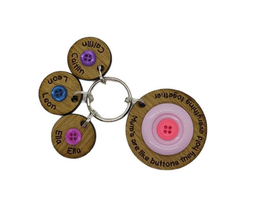 Circle keyring engraved with 'Mum's are like buttons, they hold everything together' around the edge. Two buttons in the middle, with personalised charms featuring children's names and coloured buttons.