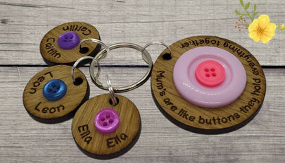 Circle keyring engraved with 'Mum's are like buttons, they hold everything together' around the edge. Two buttons in the middle, with personalised charms featuring children's names and coloured buttons.