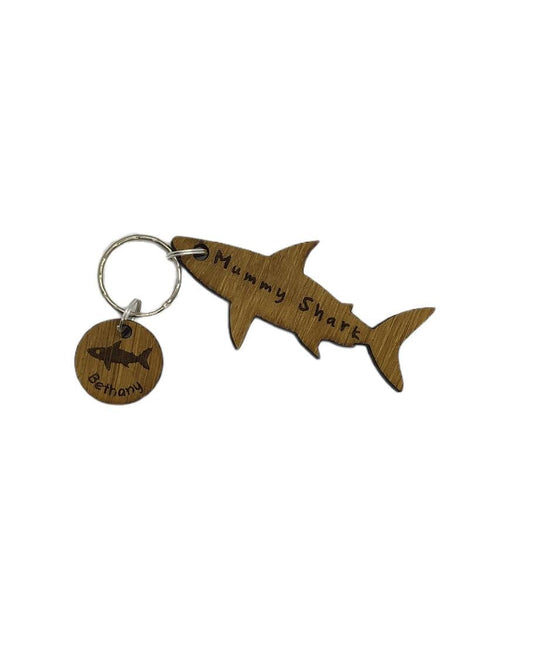 Shark-shaped keyring with "Mummy Shark" engraved, featuring child name charms around the outside and a shark in the middle.