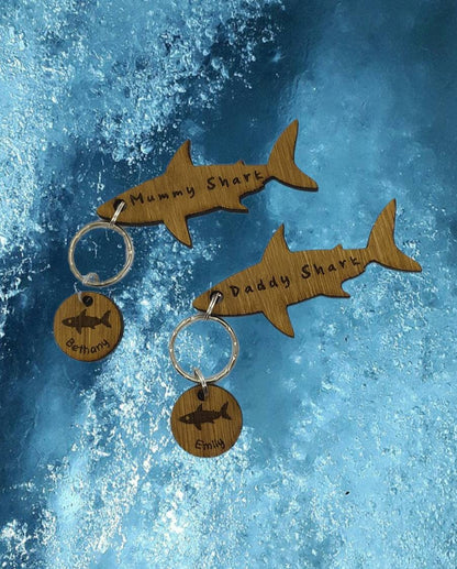 Shark-shaped keyring with "Mummy Shark" engraved, featuring child name charms around the outside and a shark in the middle.