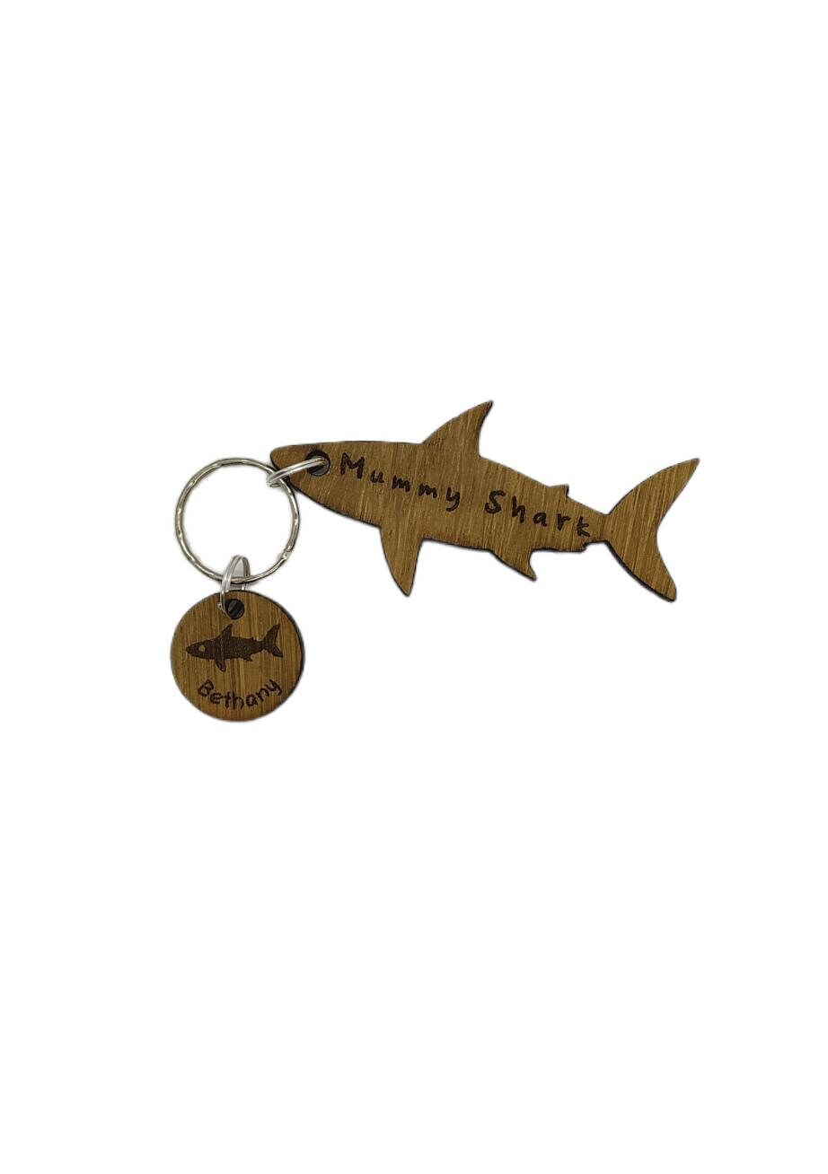 Shark-shaped keyring with "Mummy Shark" engraved, featuring child name charms around the outside and a shark in the middle.