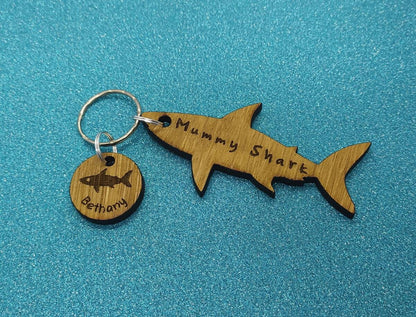 Shark-shaped keyring with "Mummy Shark" engraved, featuring child name charms around the outside and a shark in the middle.