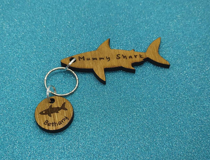 Shark-shaped keyring with "Mummy Shark" engraved, featuring child name charms around the outside and a shark in the middle.