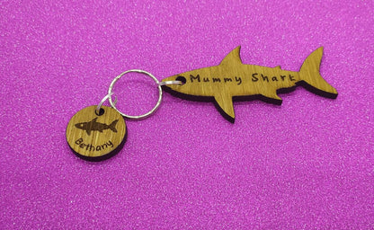 Shark-shaped keyring with "Mummy Shark" engraved, featuring child name charms around the outside and a shark in the middle.
