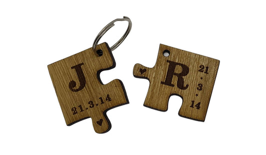 2 puzzle piece keyrings engraved with initials and a special date.