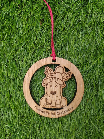 Personalised circular wooden bauble featuring a laser-engraved reindeer in the centre, with the year engraved on its hat and "First Christmas" along with a custom name engraved around the edge. Perfect keepsake ornament for the Christmas tree.