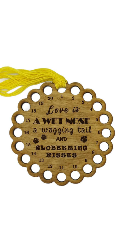 Bumpy circle-shaped thread holder with "Love is a wet nose, a wagging tail and slobbering kisses" engraved, featuring 20 holes for thread.