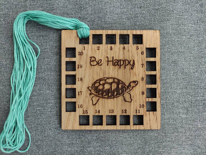 Square shape thread holder, with tortoise and "be happy" engraved in the middle. 20 holes for thread. 