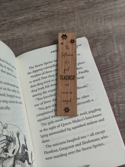Wooden bookmark engraved with the quote "The influence of a good TEACHER can never be erased," featuring floral designs and a coloured ribbon at the bottom.