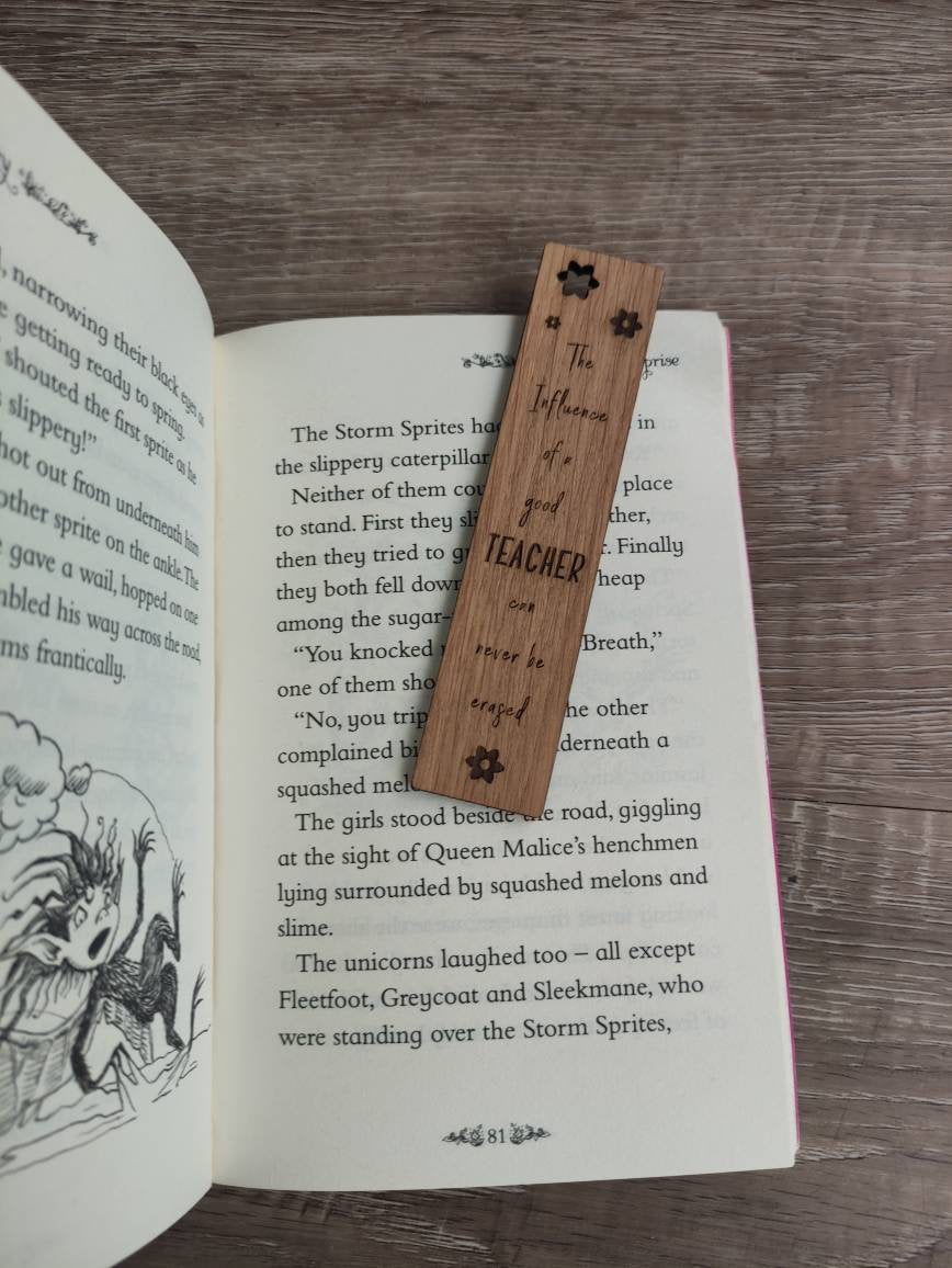 Wooden bookmark engraved with the quote "The influence of a good TEACHER can never be erased," featuring floral designs and a coloured ribbon at the bottom.