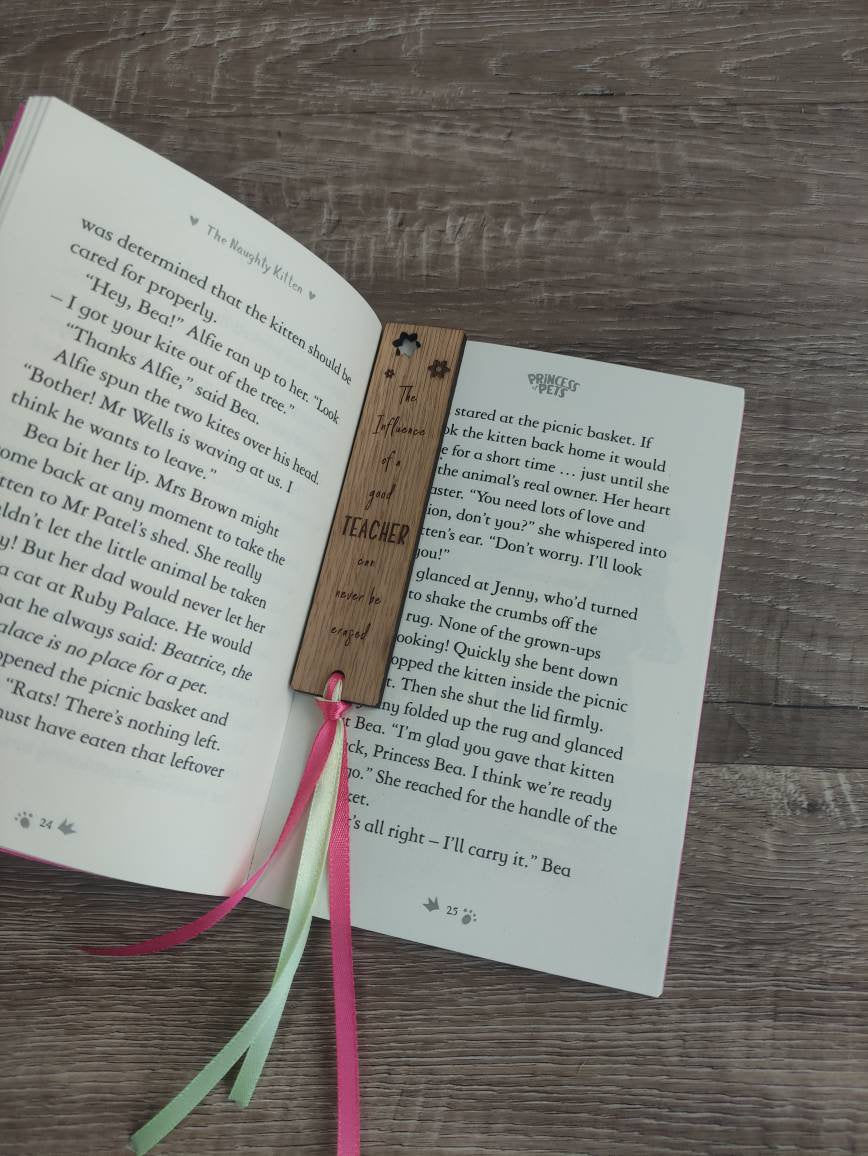 Wooden bookmark engraved with the quote "The influence of a good TEACHER can never be erased," featuring floral designs and a coloured ribbon at the bottom.