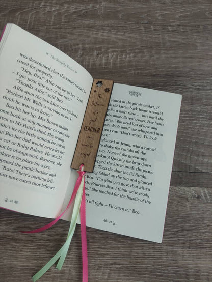 Wooden bookmark engraved with the quote "The influence of a good TEACHER can never be erased," featuring floral designs and a coloured ribbon at the bottom.