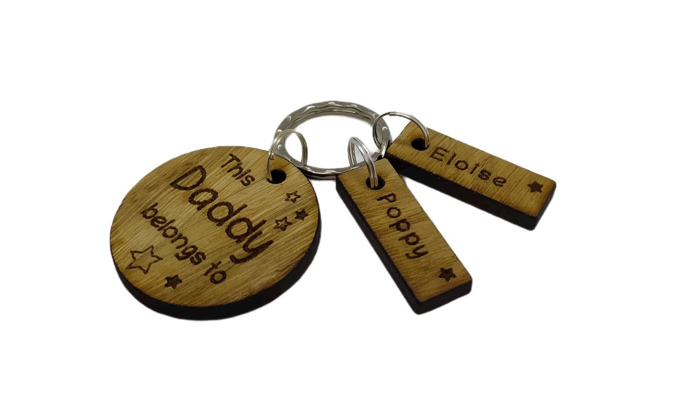 This Daddy Belongs To keychain with added charms, engraved with names and a star.