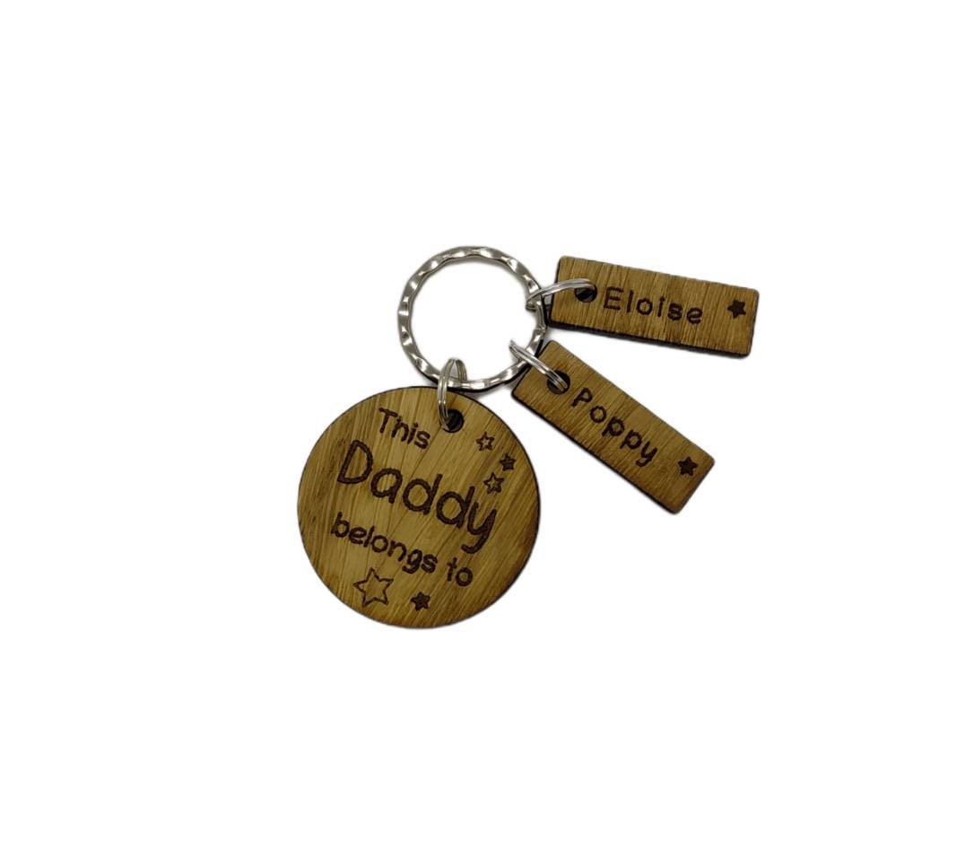 This Daddy Belongs To keychain with added charms, engraved with names and a star.